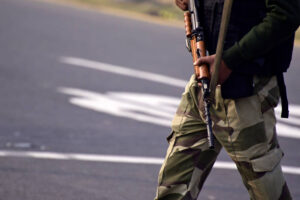 Security guard with rifle standing on outside to protect the area.
